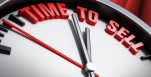 Close-up of clock hands approaching midnight with red text above.